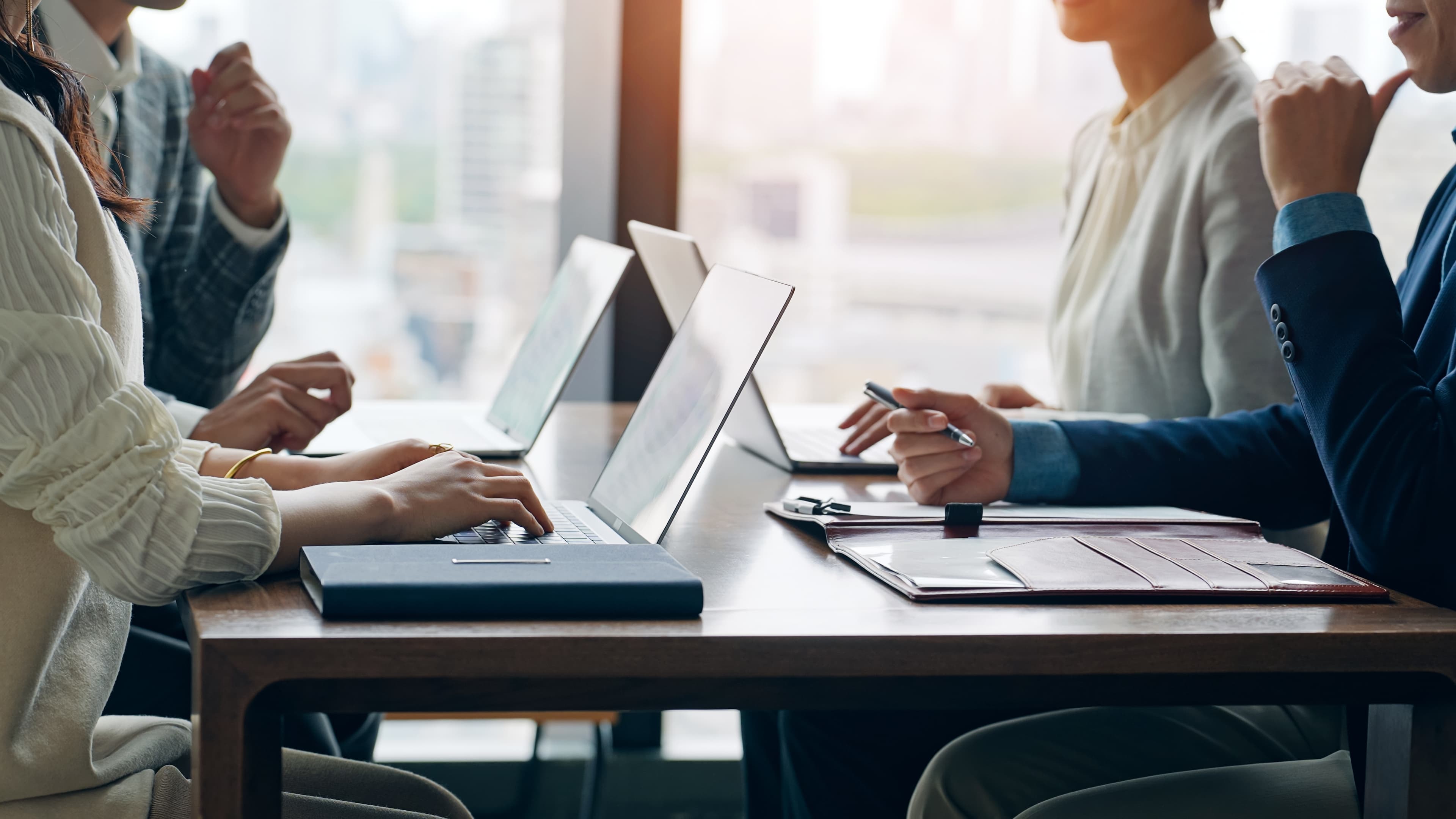 Samtale omkring et bord med computere og dokumenter
